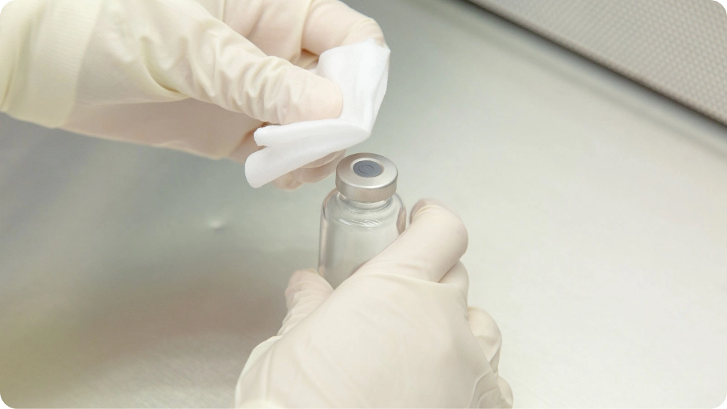 Gloved hands swabbing a small machine part