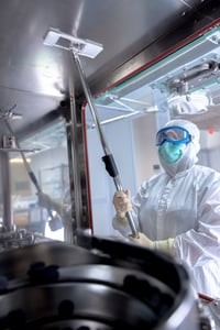 man in hazmat suit cleaning metal ceiling with swiffer mop